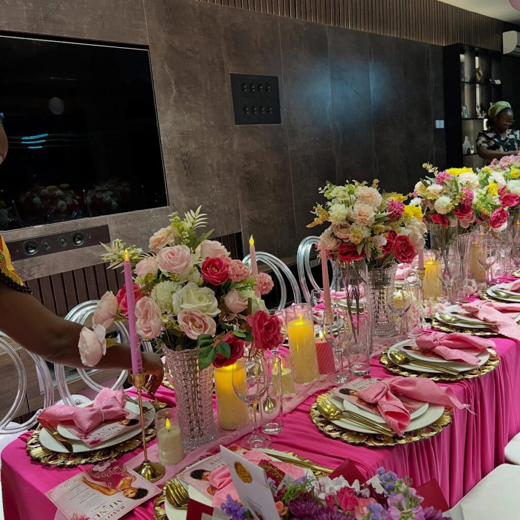 Elegant dining table with pink tablecloth, gold plates, and lush rose centerpieces.
