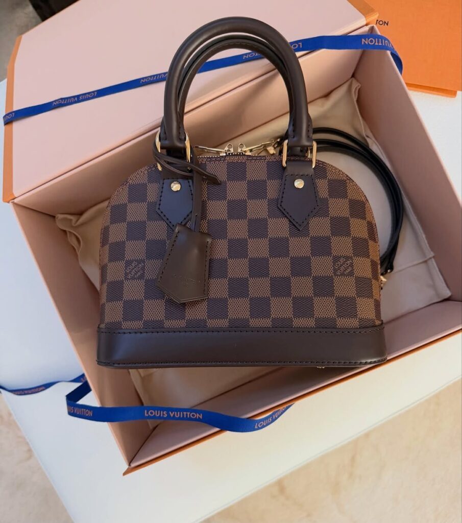 Louis Vuitton checkered handbag inside a branded pink and orange gift box