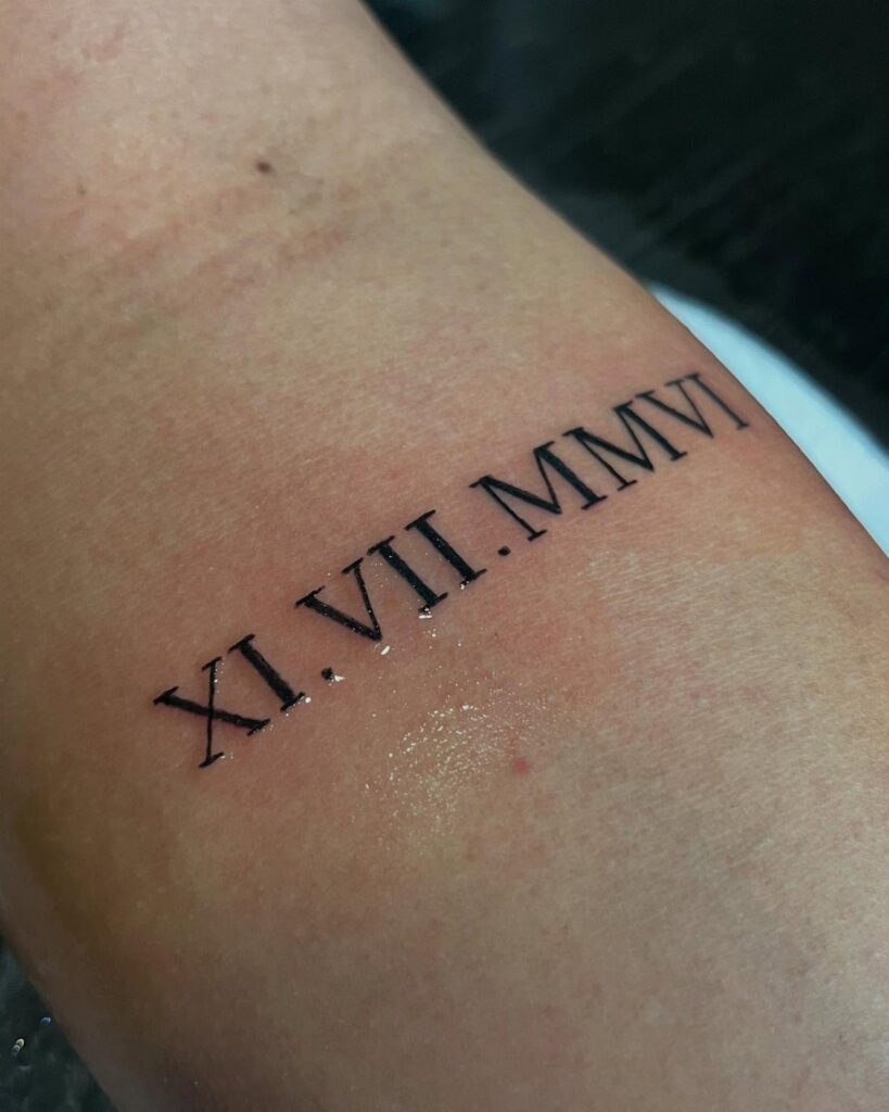 Roman numeral tattoo on skin showing the date XI.VII.MMVI in black ink.
