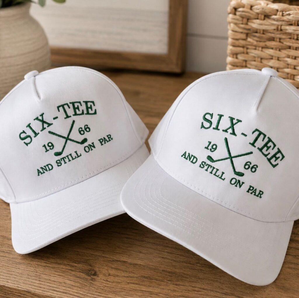 Two white baseball caps with green golf-themed embroidery for a 60th birthday.