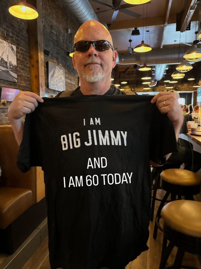 Man holding a black t-shirt that says I am Big Jimmy and I am 60 today