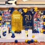 Birthday party decoration with gold and blue balloons, photo wall, and large 70 numbers