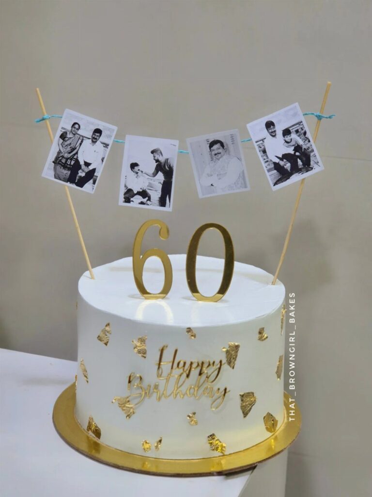White birthday cake with gold 60 topper and hanging black and white photos